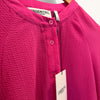 Close-up of a pink shirt with 'Essentiel Antwerp' label on a hanger.