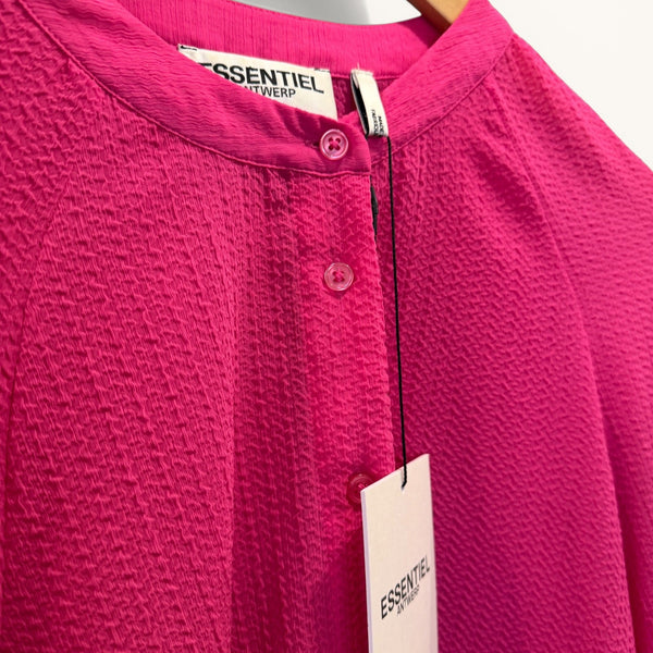 Close-up of a pink shirt with 'Essentiel Antwerp' label on a hanger.